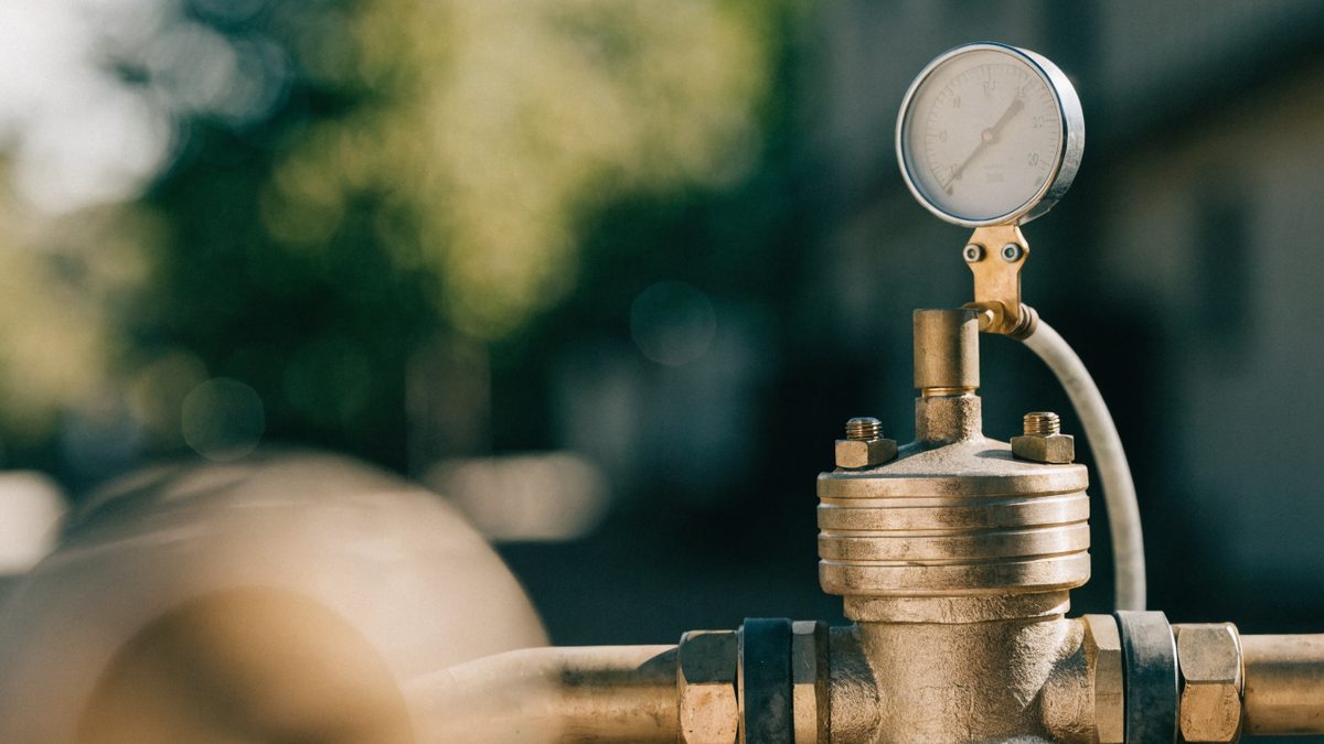 Close-up of a brass backflow preventer valve assembly with a test gauge attached