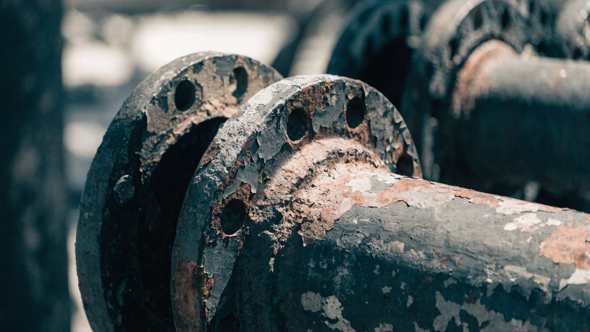 Close-up of a rusted, flaking cast iron pipe joint
