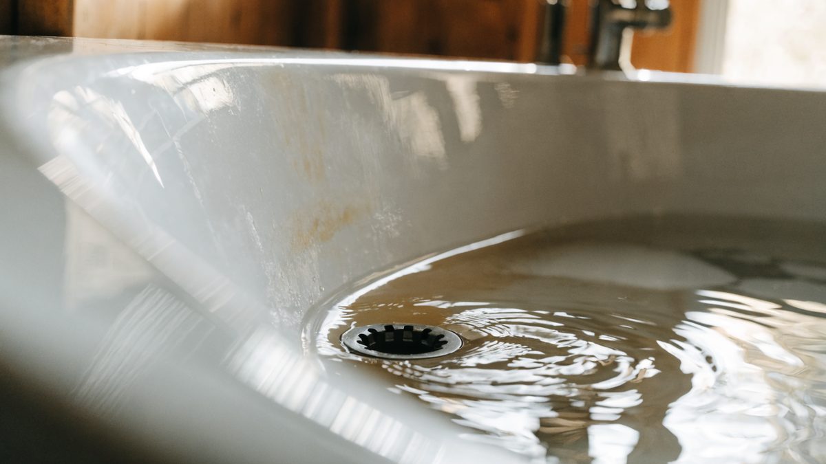Close-up of a slow-draining bathtub with standing water near the drain