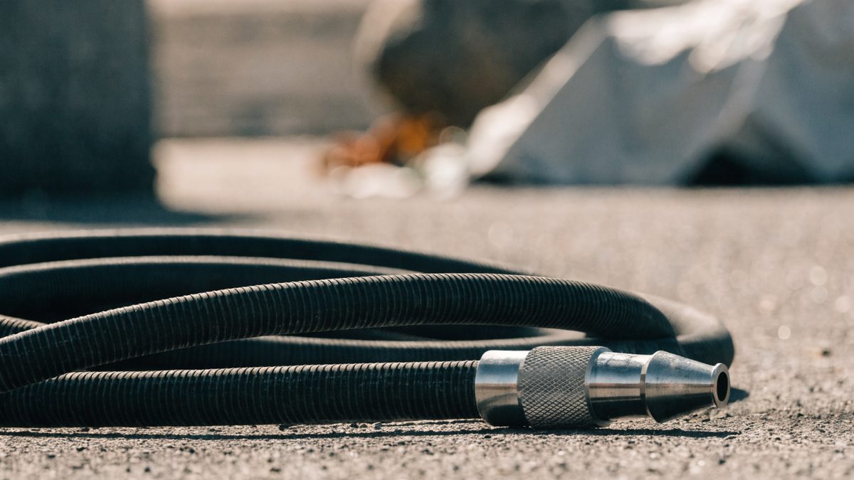 Close-up of a high-pressure jetting hose nozzle coiled on the ground