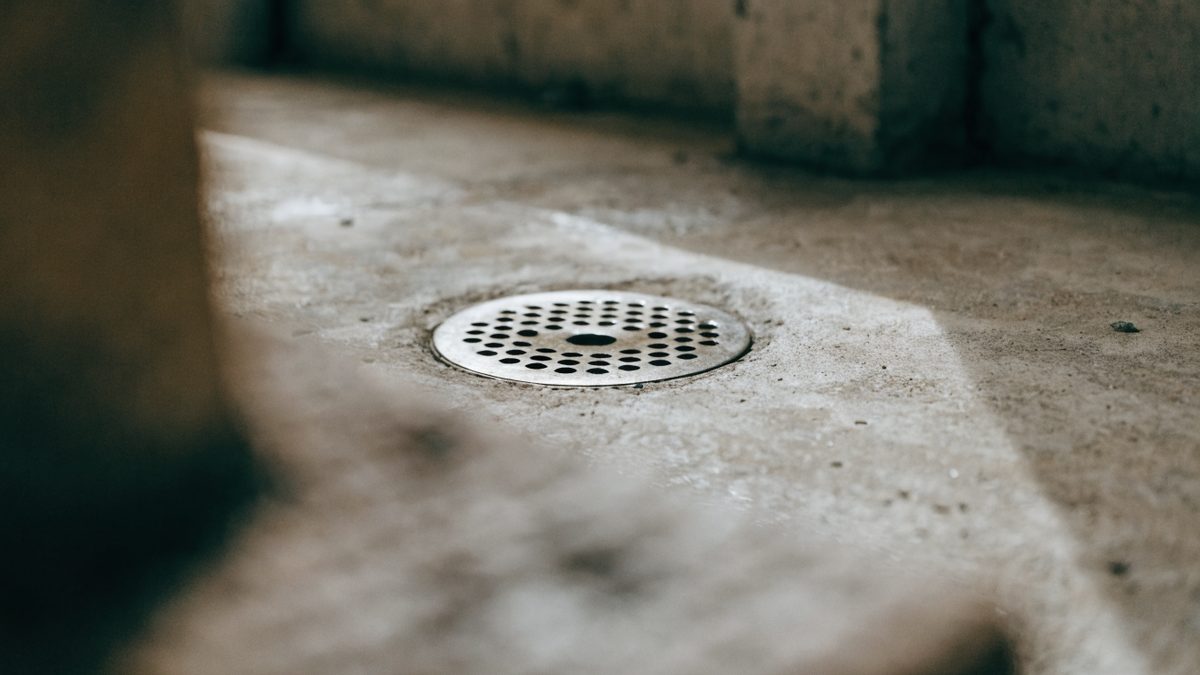 Close-up of a round floor drain grate set into a concrete basement floor