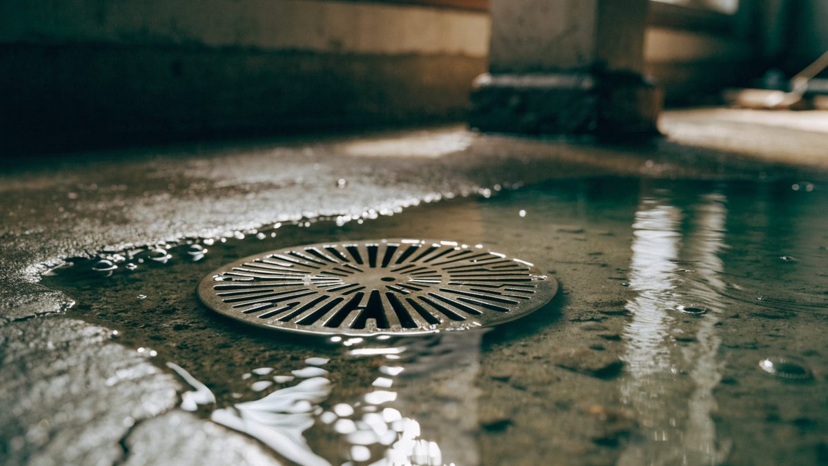 Close-up of water slowly pooling around a basement floor drain grate