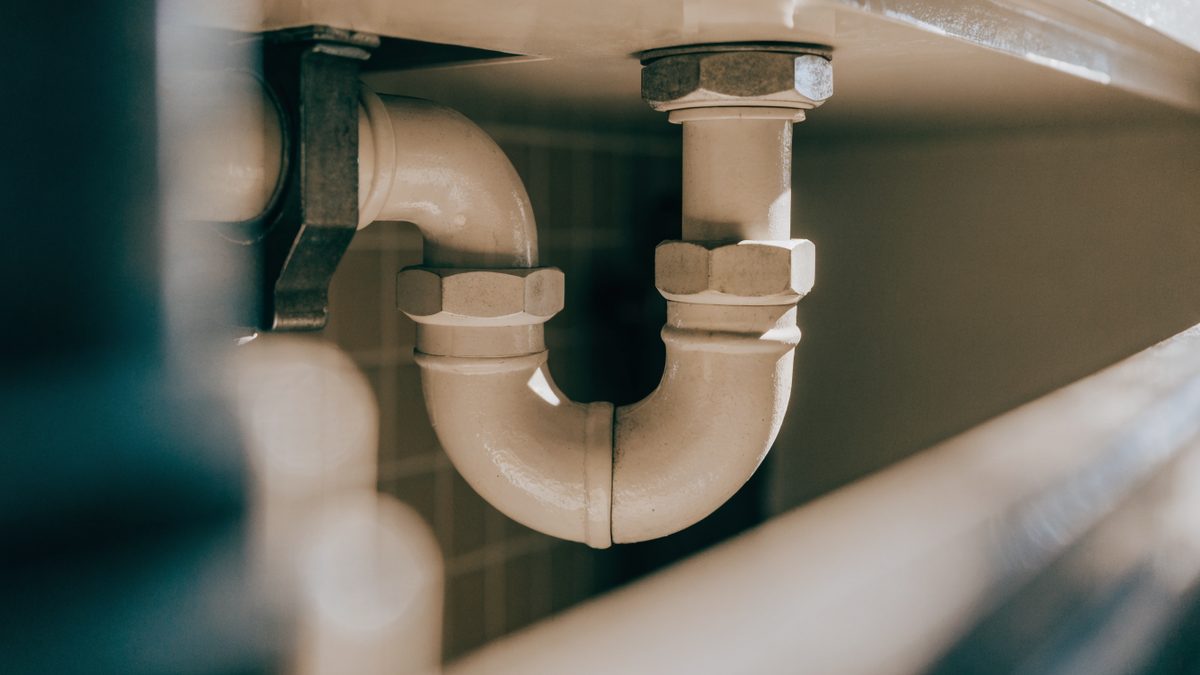 Close-up of a dry P-trap pipe fitting under a bathroom sink