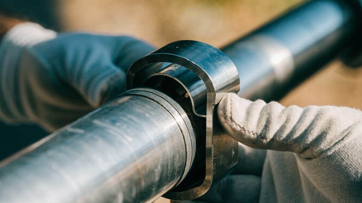 Close-up of a stainless repair coupling clamp being fitted onto a pipe joint